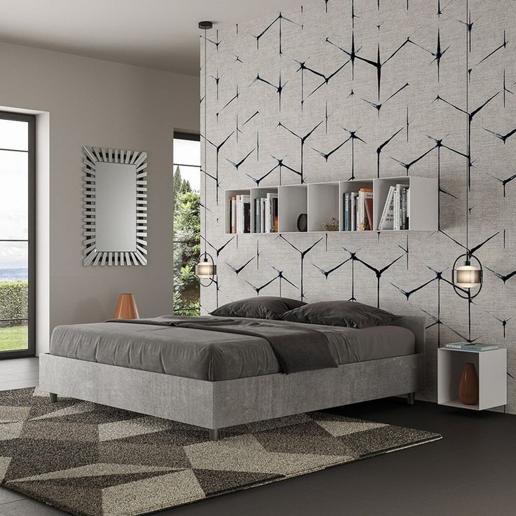 Camera da letto con letto grigio, parete decorata con motivi, tappeto geometrico e una grande finestra con vista sul paesaggio.