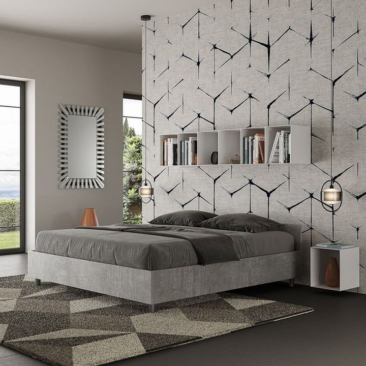 Camera da letto con letto grigio, parete decorata con motivi, tappeto geometrico e una grande finestra con vista sul paesaggio.