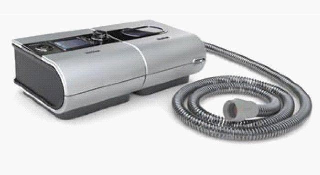 Silver CPAP machine with hose, used for sleep apnea treatment.