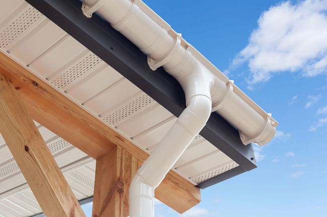 A white gutter on the roof of a house under construction.