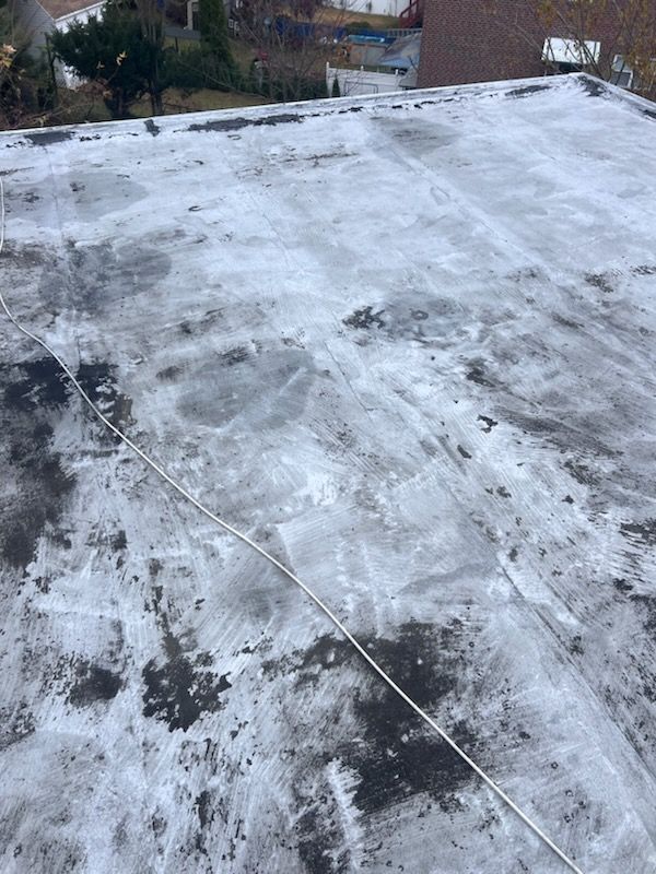 Flat roof covered in white substance; part black, rope-like object across the surface.
