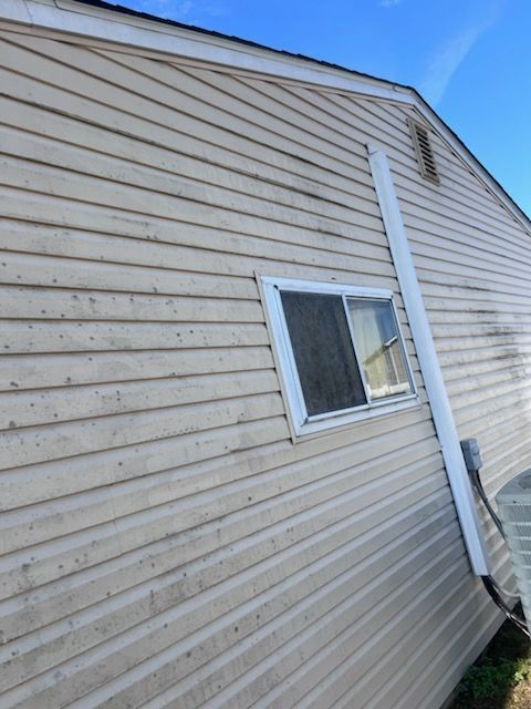 Beige siding on a house, window with a white frame, and a white drain pipe on the side.
