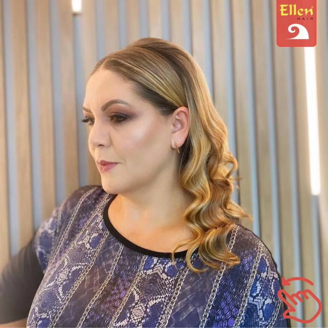 Mulher com cabelos loiros ondulados e maquiagem esfumada nos olhos, usando uma blusa estampada em azul e preto.