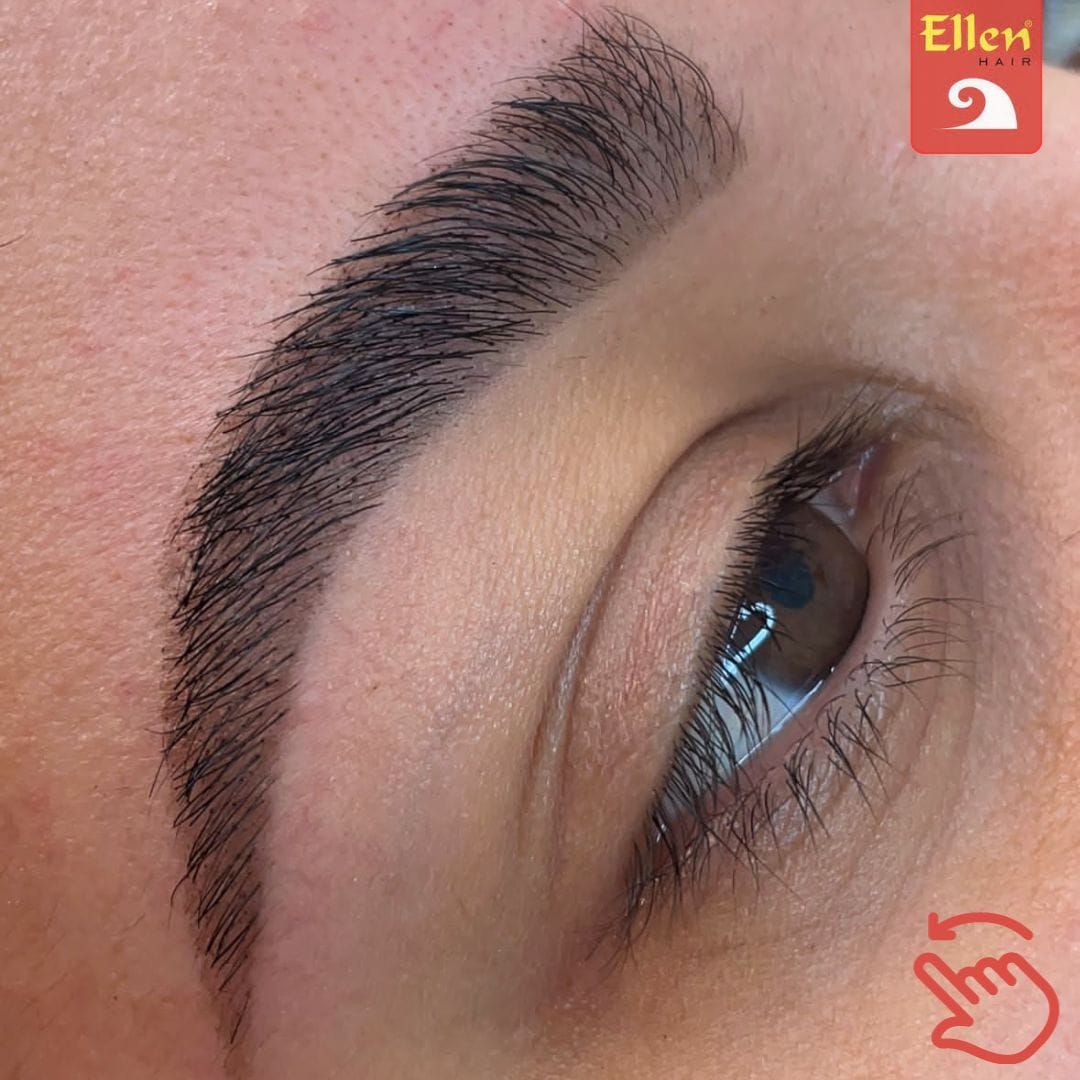 Close de uma sobrancelha com microblading. Traços escuros e texturizados criam uma sobrancelha cheia e natural acima do olho.