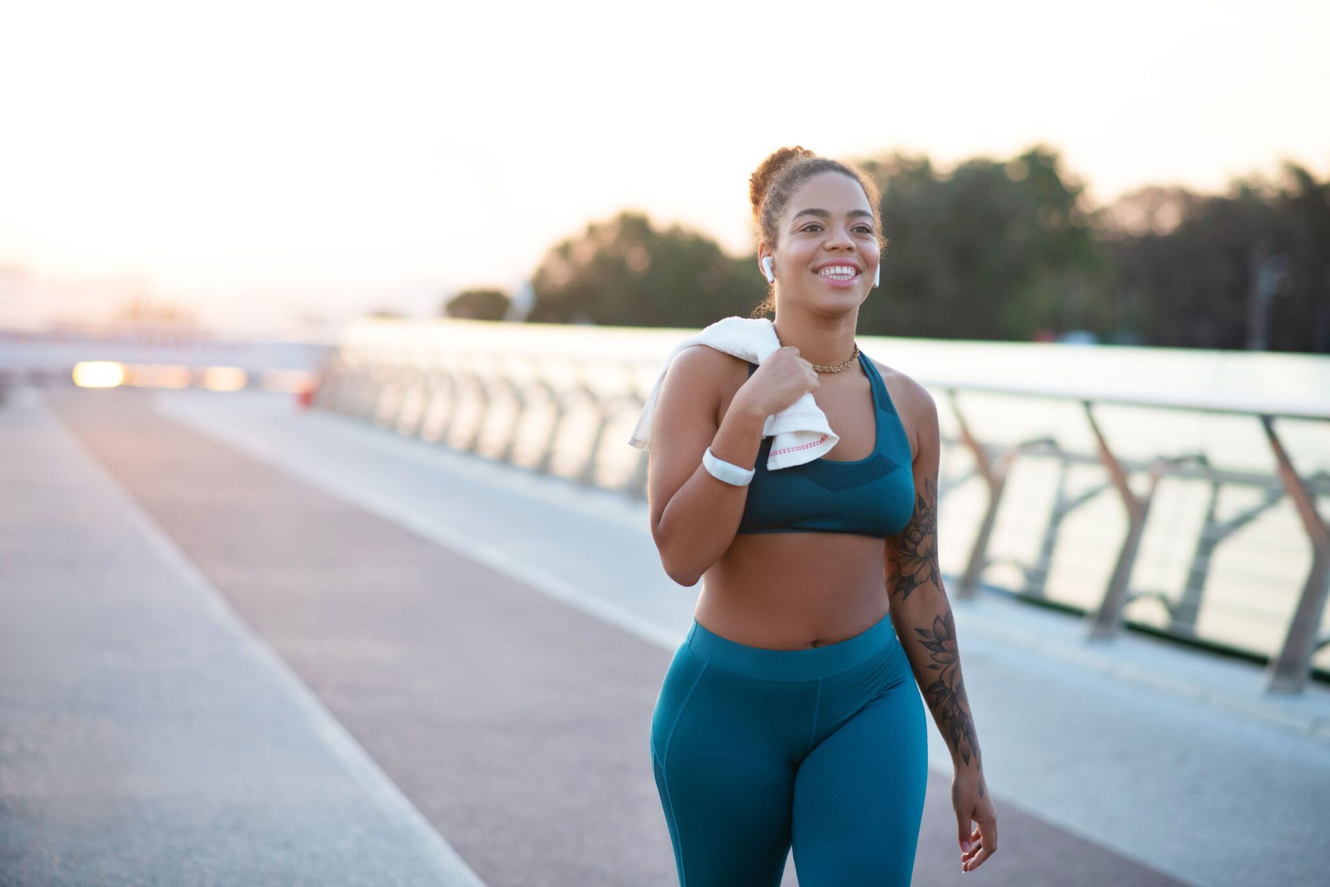 A woman is walking on a bridge with a towel around her neck.