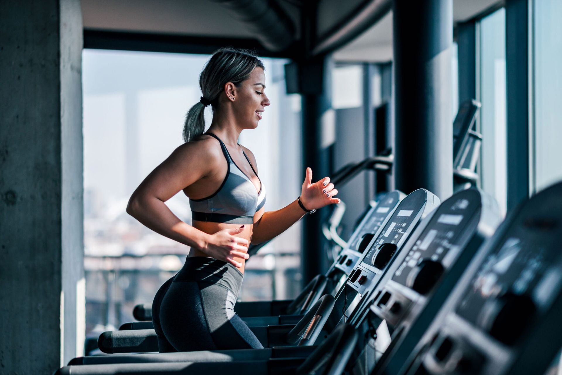 A woman is running on a treadmill in a gym.