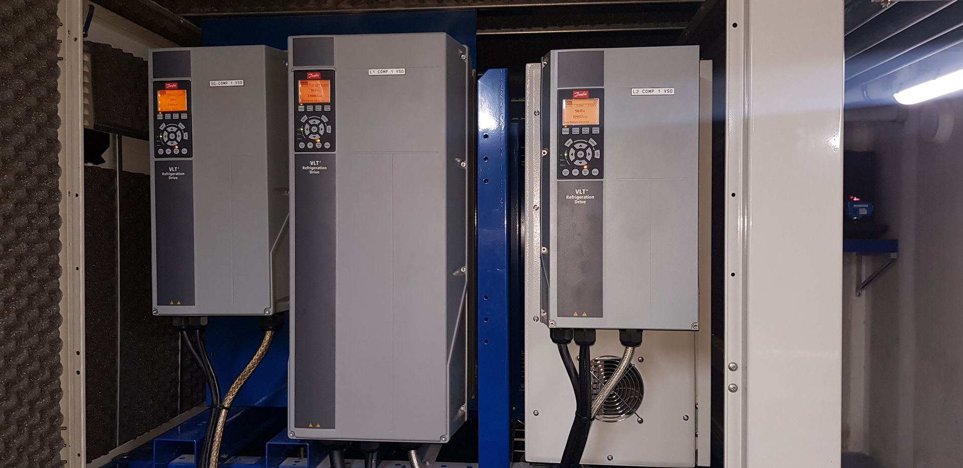 Three electrical boxes are sitting next to each other in a room.