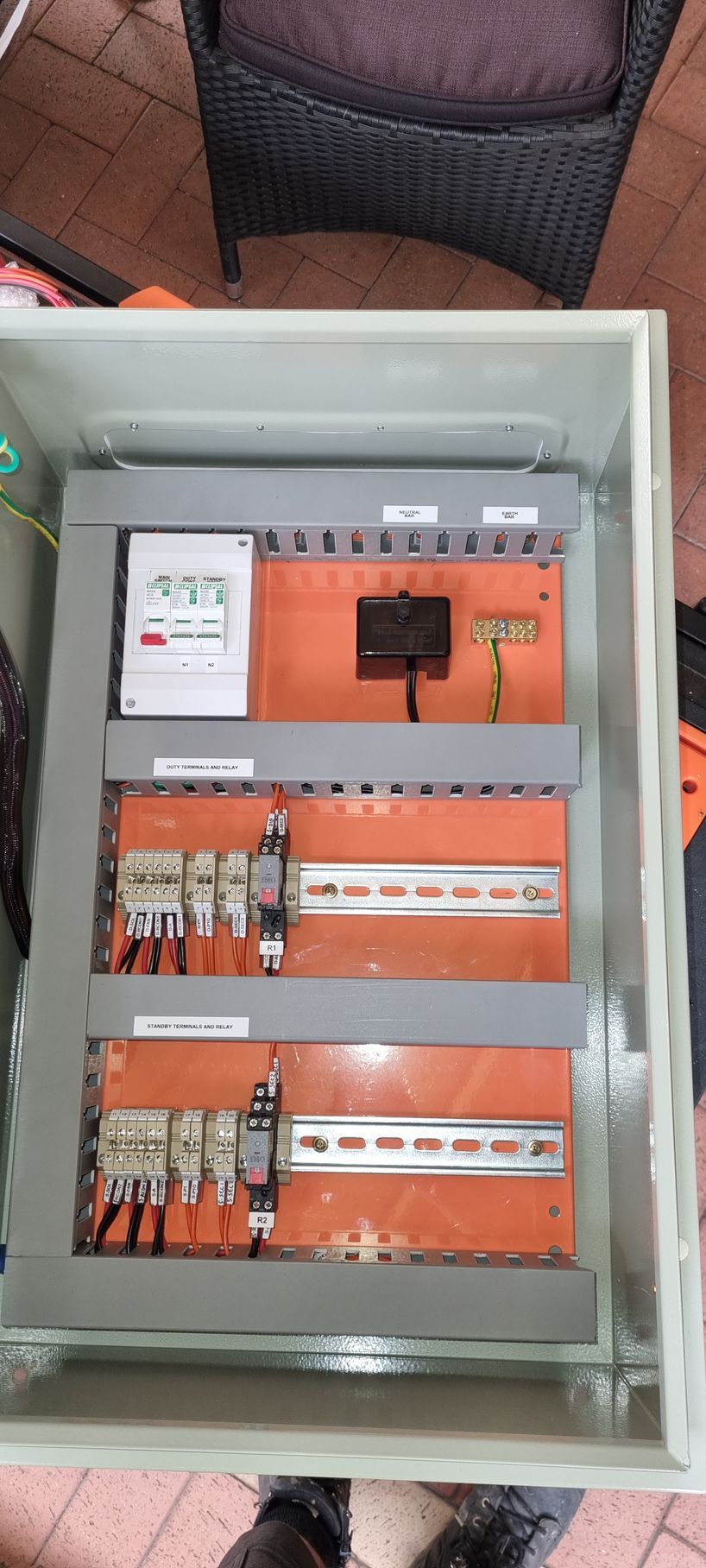 A person is standing next to a box of electrical equipment.