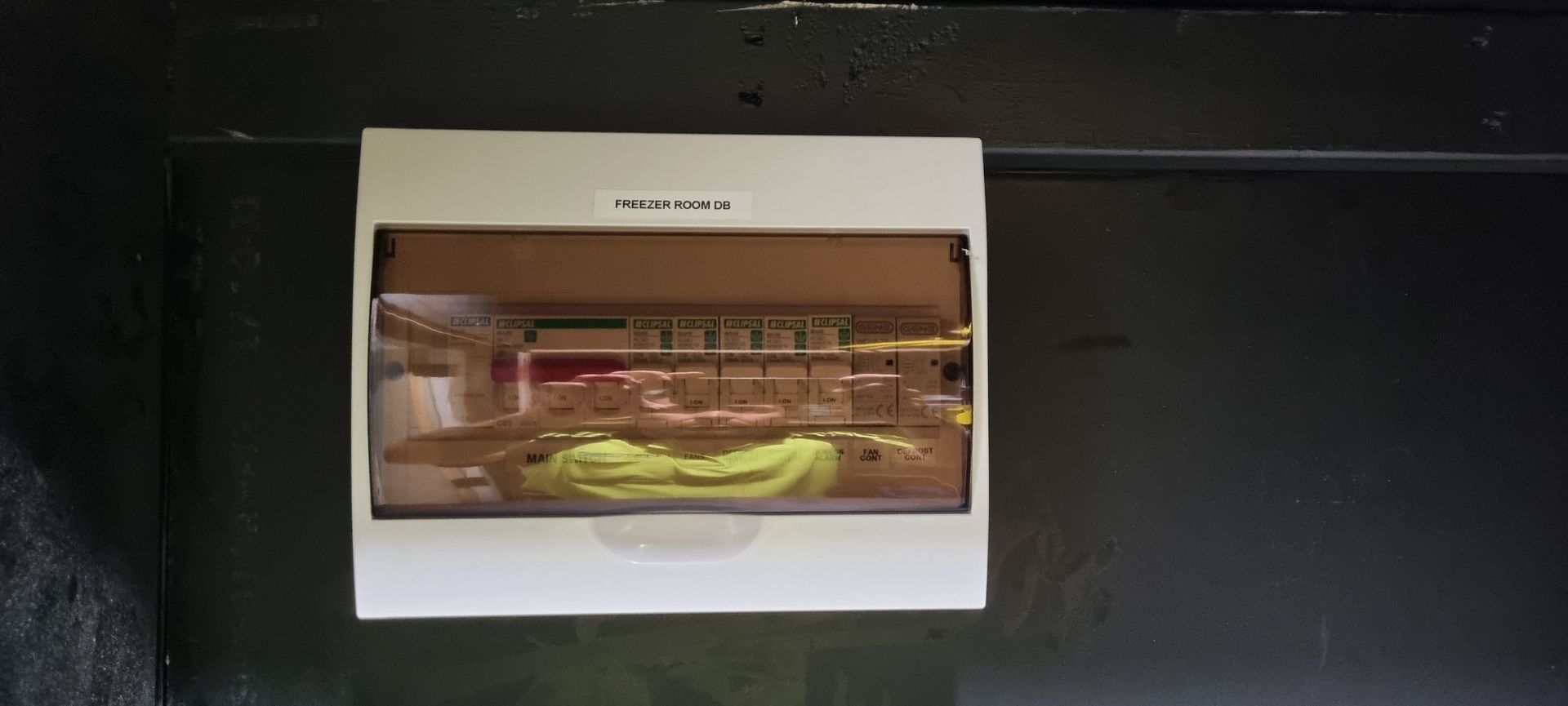 A white box is hanging on a black wall.