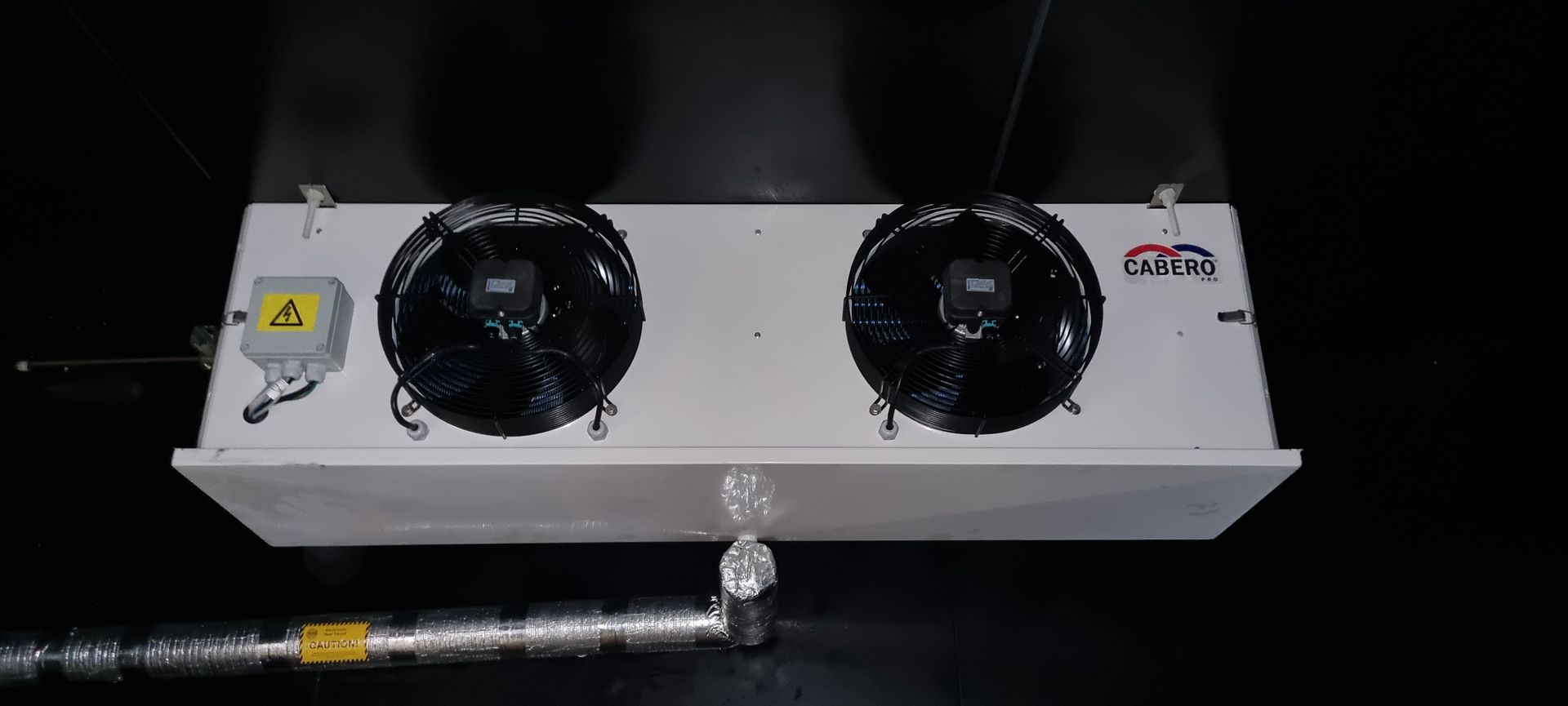 A white box with two fans attached to it is hanging from the ceiling.