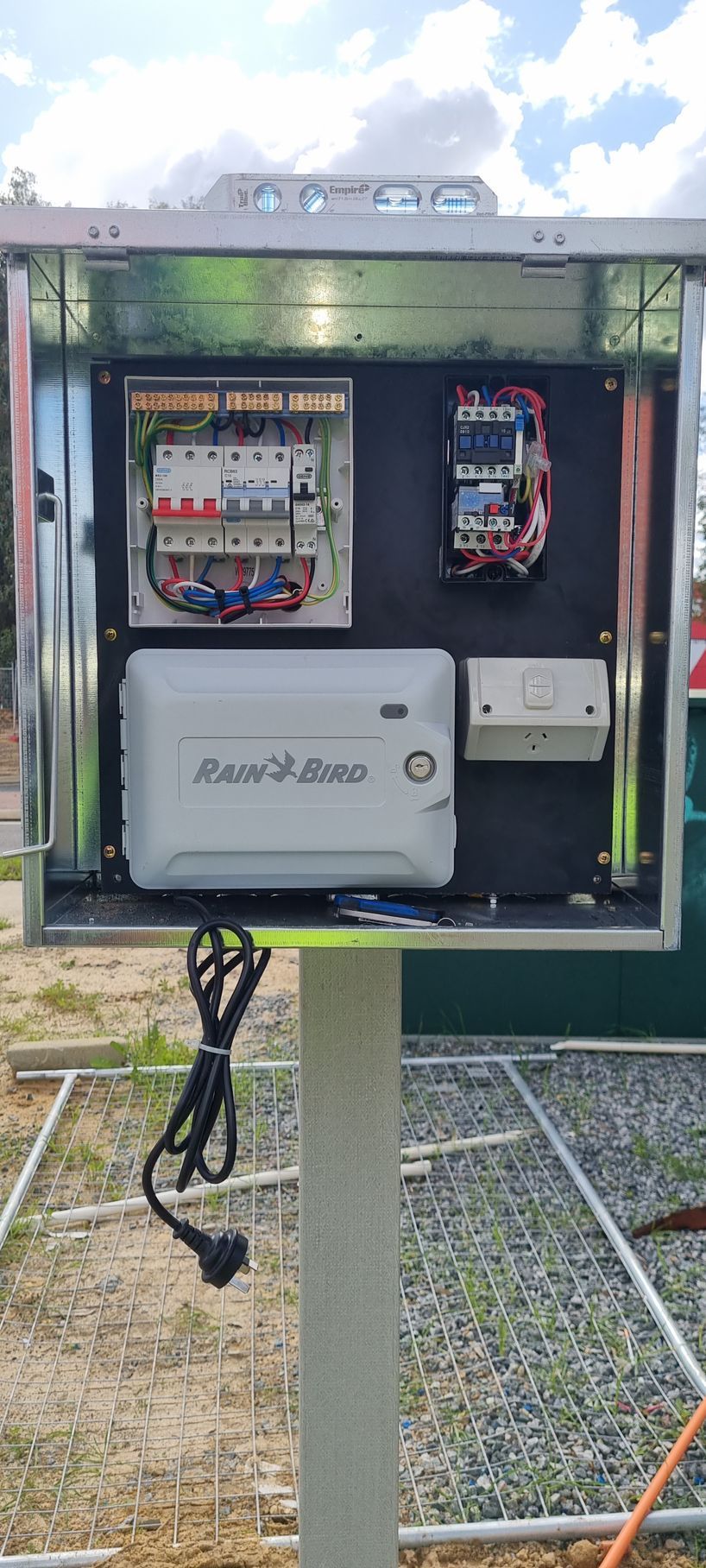 A electrical box is sitting on top of a pole.