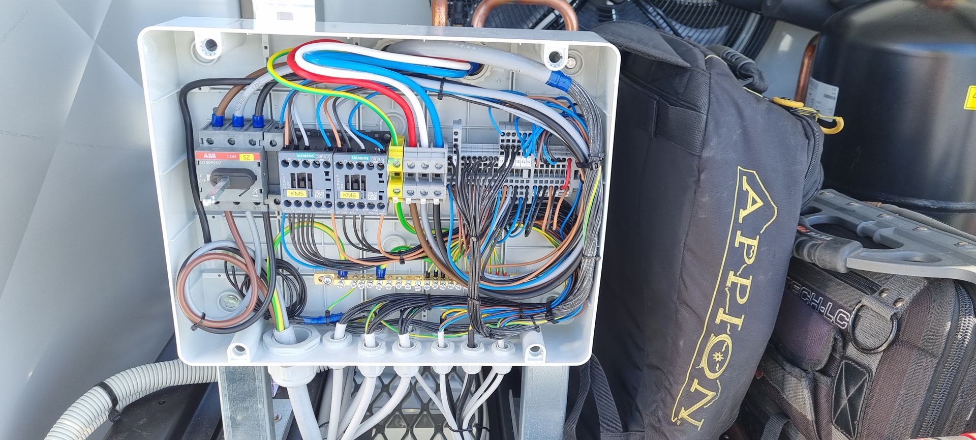 A box with a lot of wires in it is sitting on top of a car.