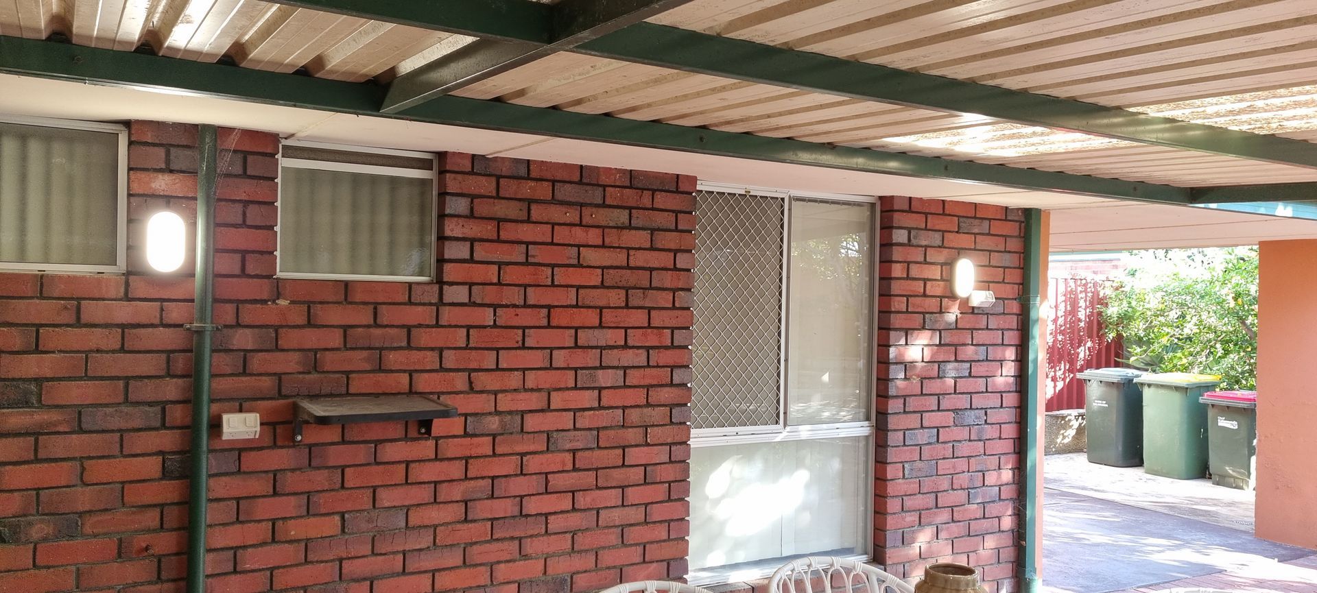 A brick wall with a roof and a couch in front of it.