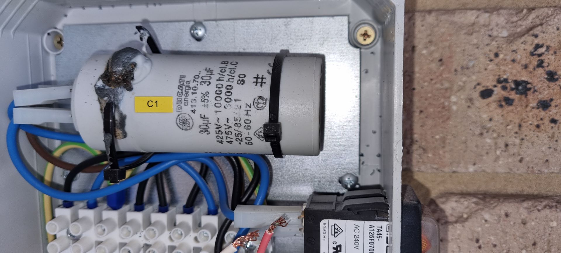 A close up of a electrical box with a capacitor in it.