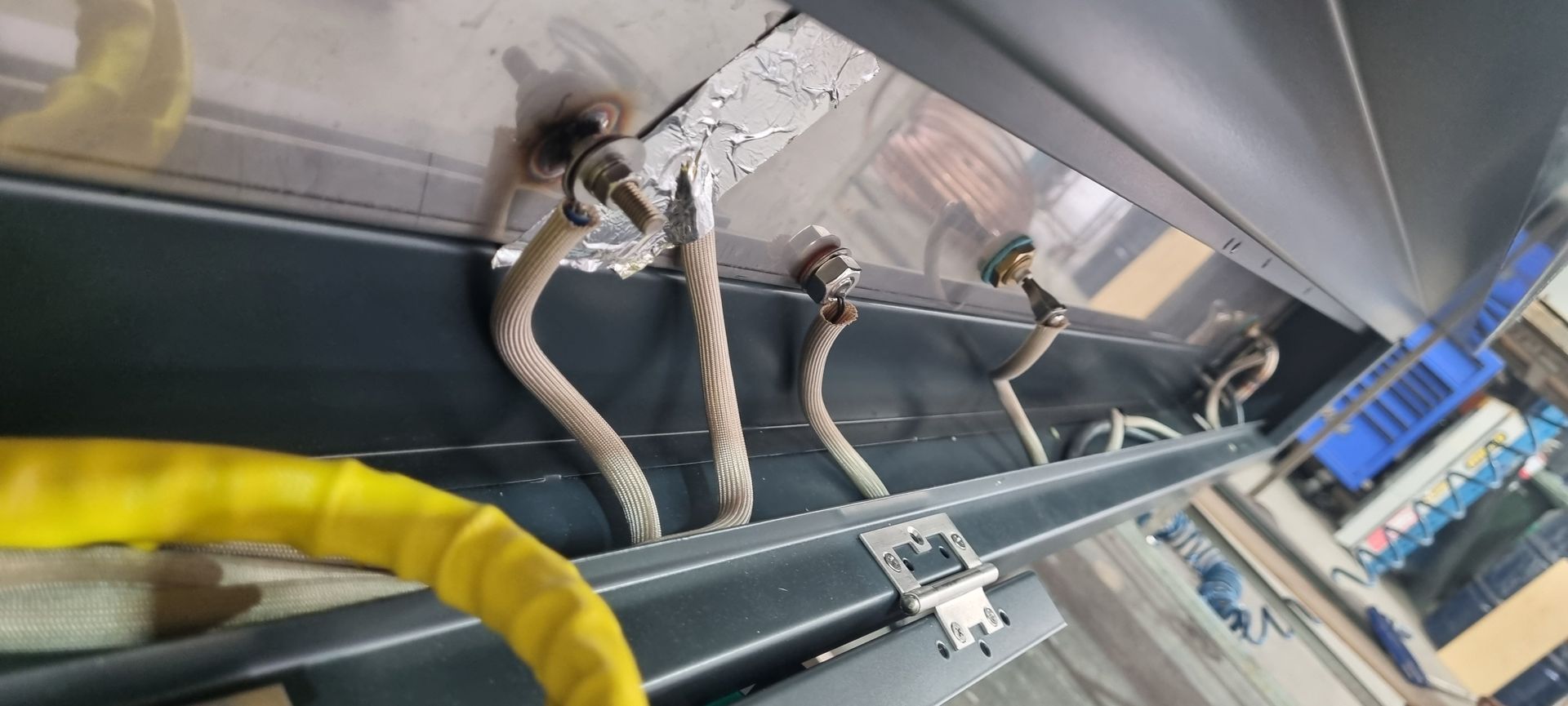 A bunch of wires are hanging from a metal shelf.