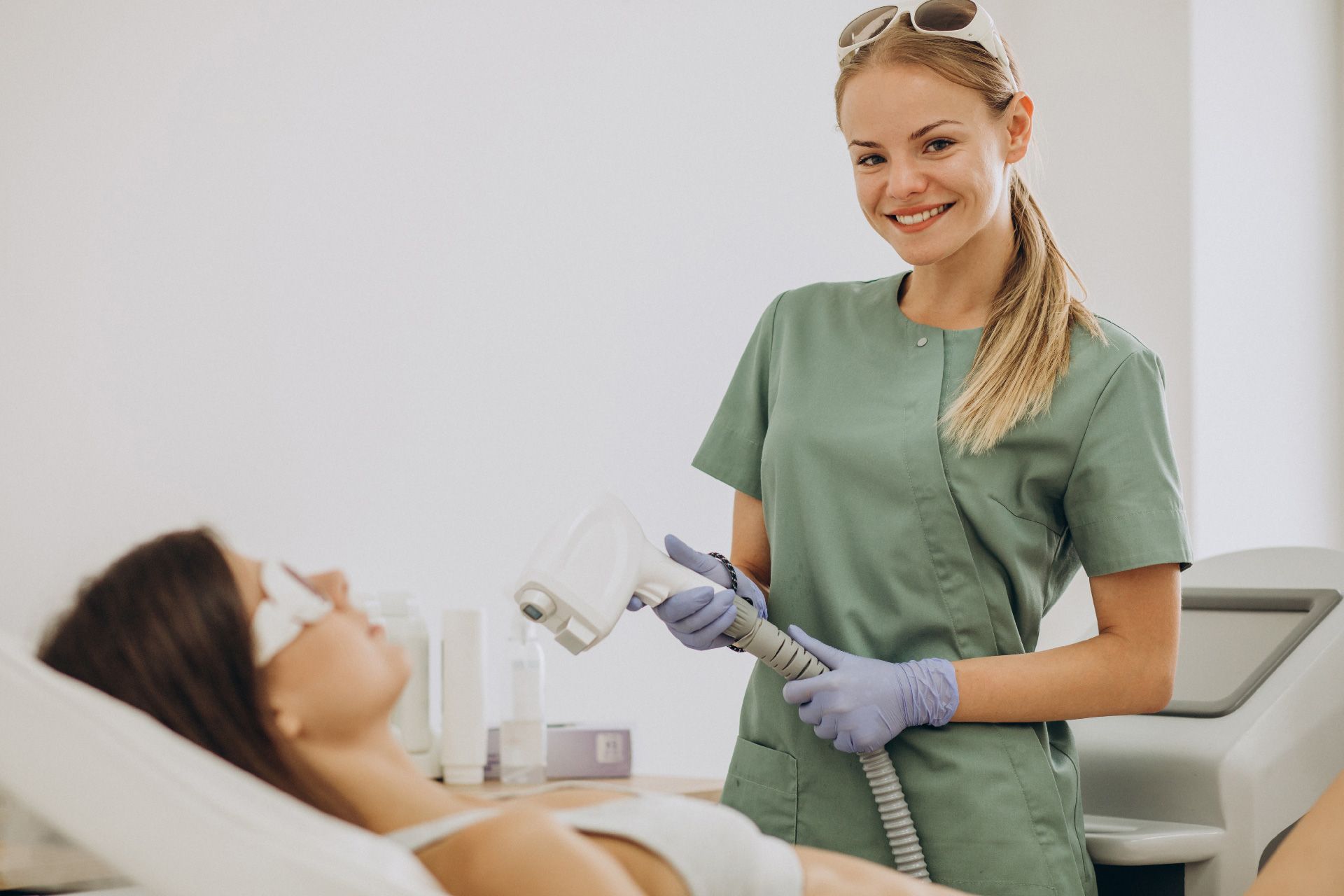 Mujer realizando depilación láser a un cliente en un entorno médico.