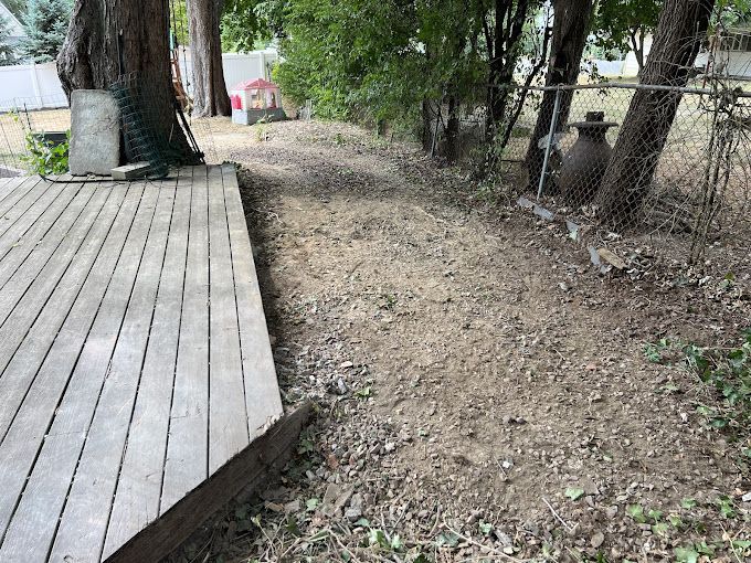 A wooden deck is sitting next to a dirt path surrounded by trees.