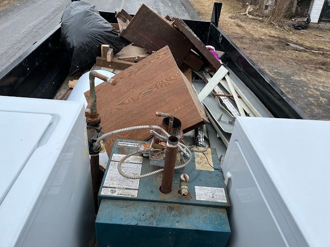 A dumpster filled with a lot of junk including a washer and dryer