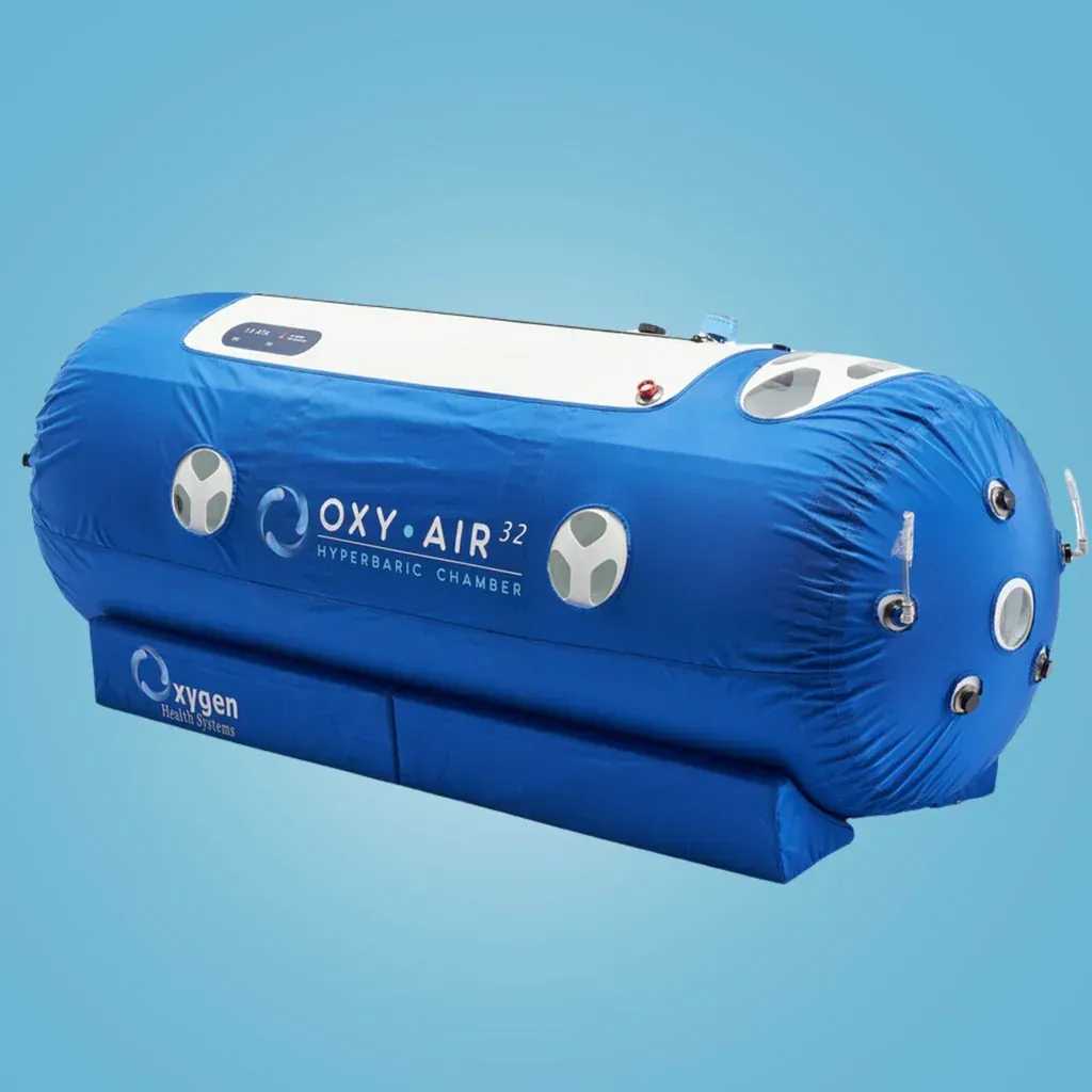 Blue and white Oxy-Air 32 hyperbaric chamber with portholes and controls, set against a light blue background.