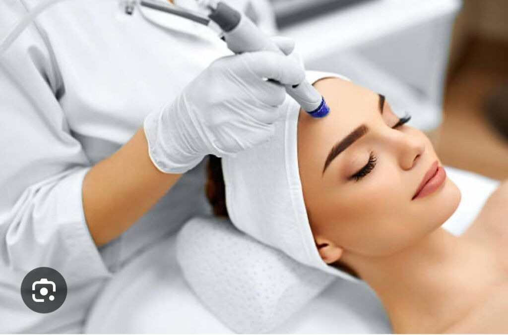 Person receiving a facial treatment with a handheld device; setting is a spa.