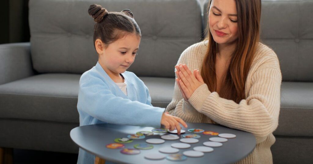 Woman and child playing a matching game at a small table indoors.
