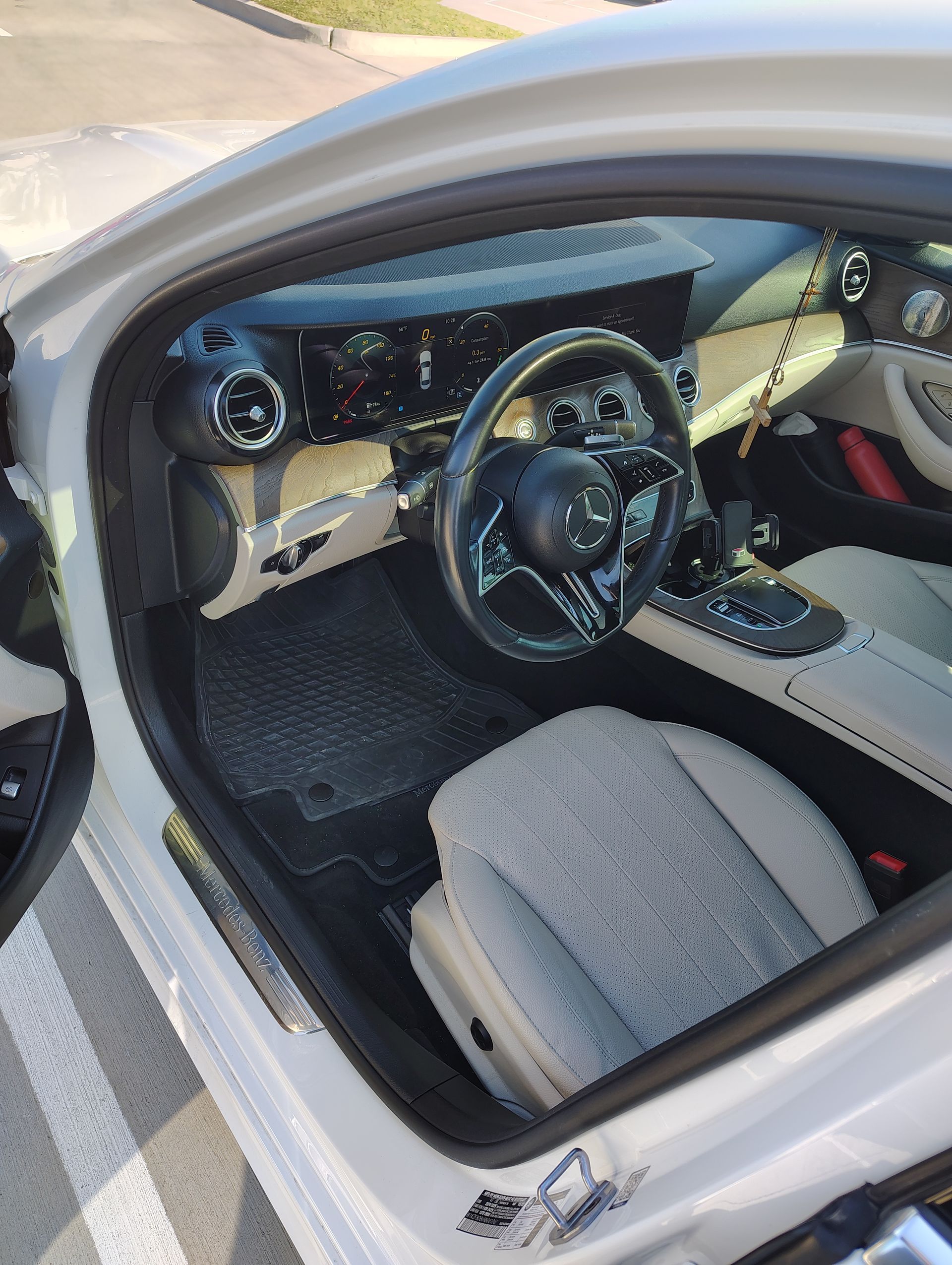 The inside of a white car with the door open and the steering wheel visible.