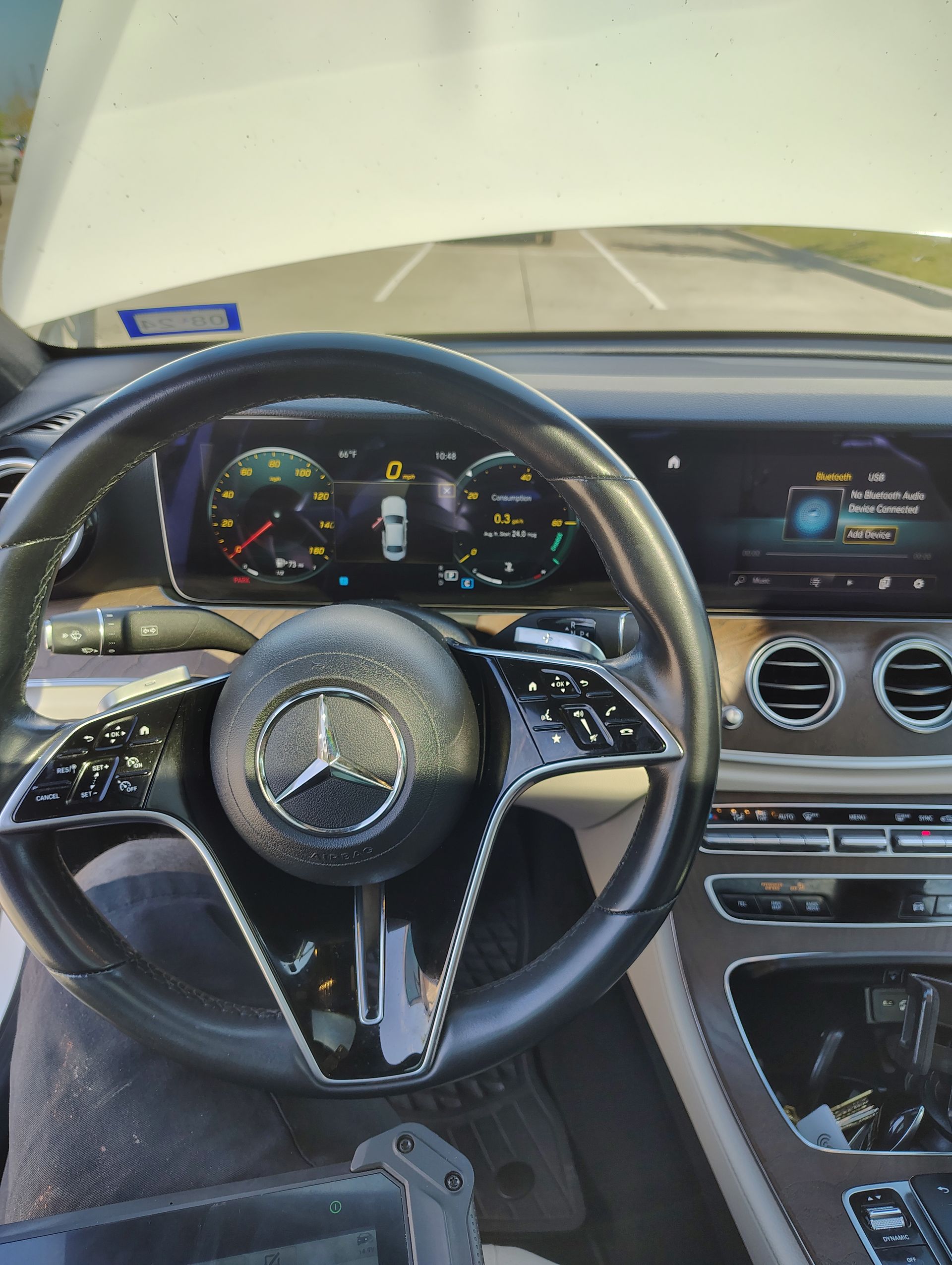 A person is driving a mercedes with the hood open.