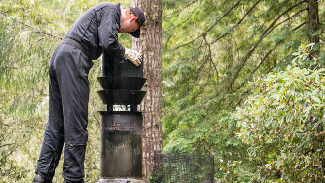 A man is working on a chimney in the woods.