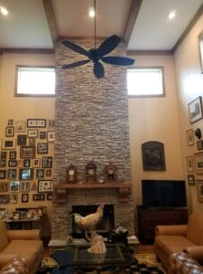 Rustic stone fireplace remodel with wooden mantel and chimney restoration.