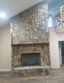 Floor-to-ceiling stone fireplace after professional masonry repair and remodeling.