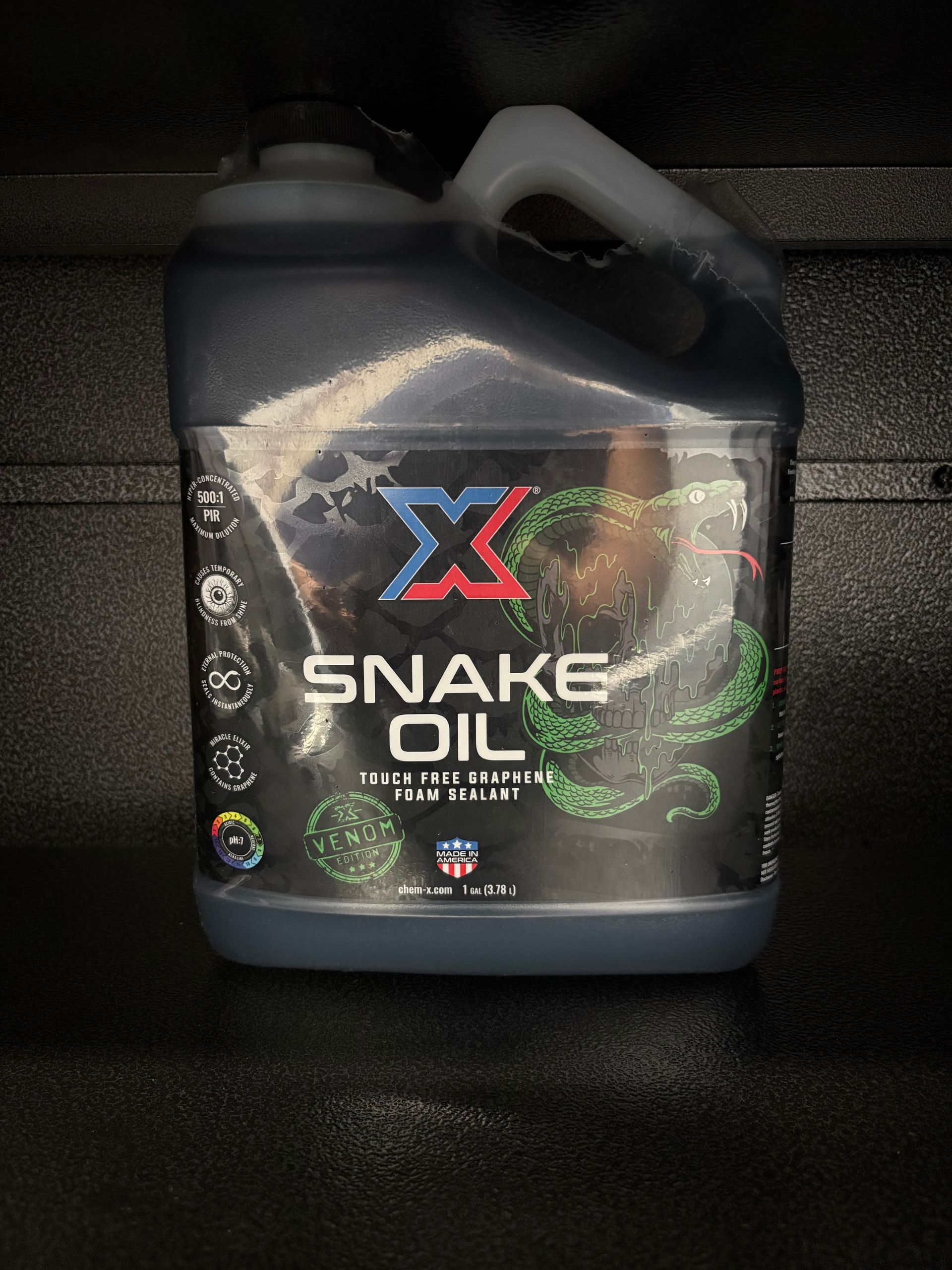 Black snake oil jug with handle and colorful label on a dark background