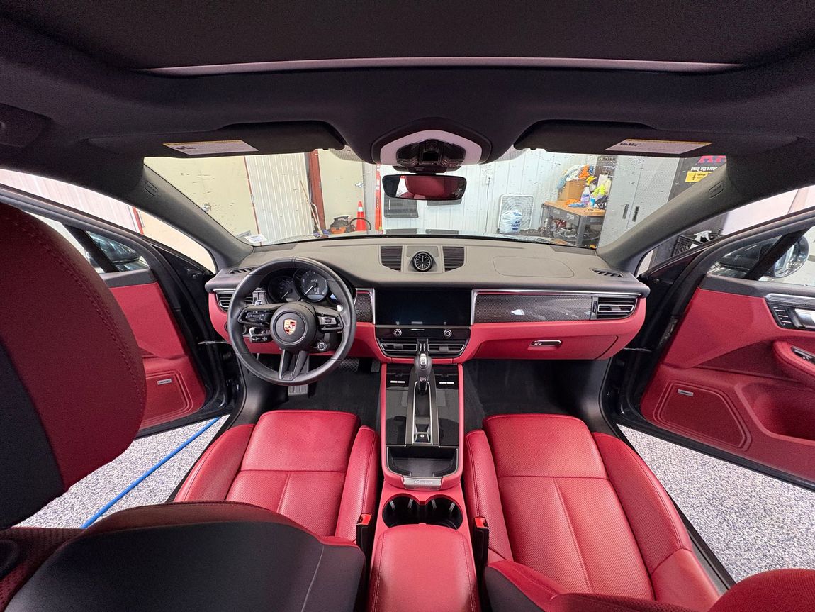 Red leather car interior viewed from back seat, showing dashboard, steering wheel, and sunroof.