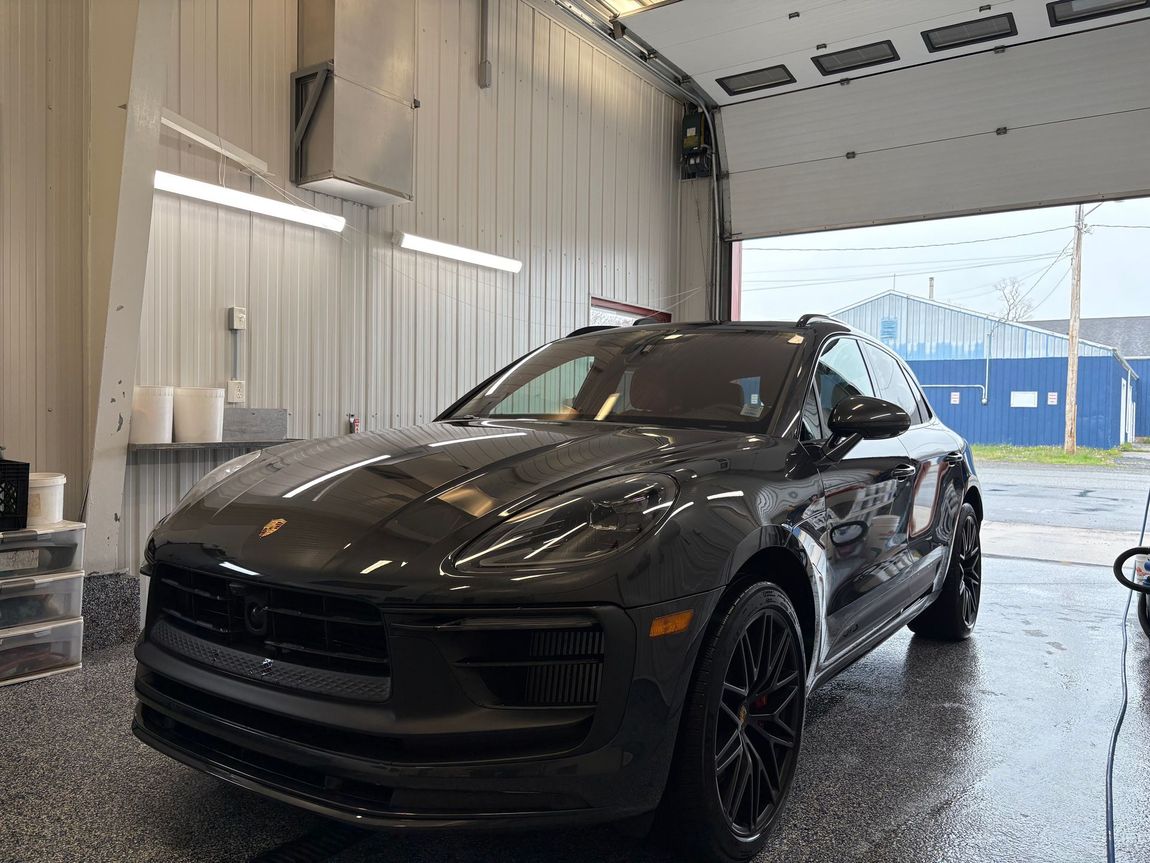 Black SUV parked inside a car wash bay with wet floor and bright overhead lights