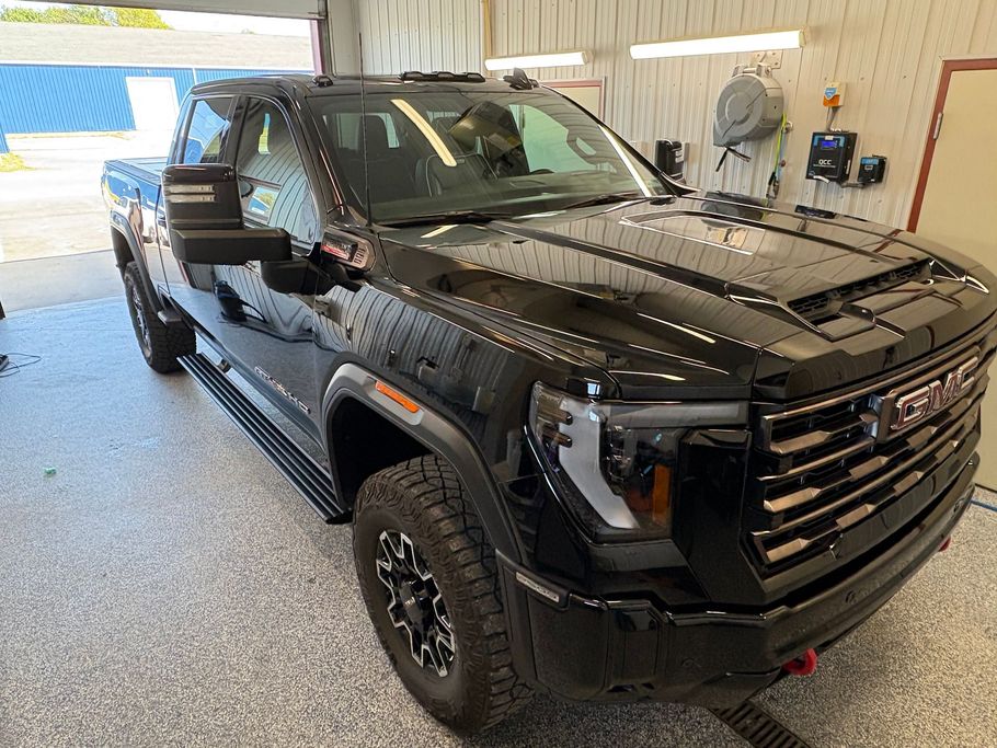 Black pickup truck in a garage, front-left view, with rugged tires and a chrome grille.