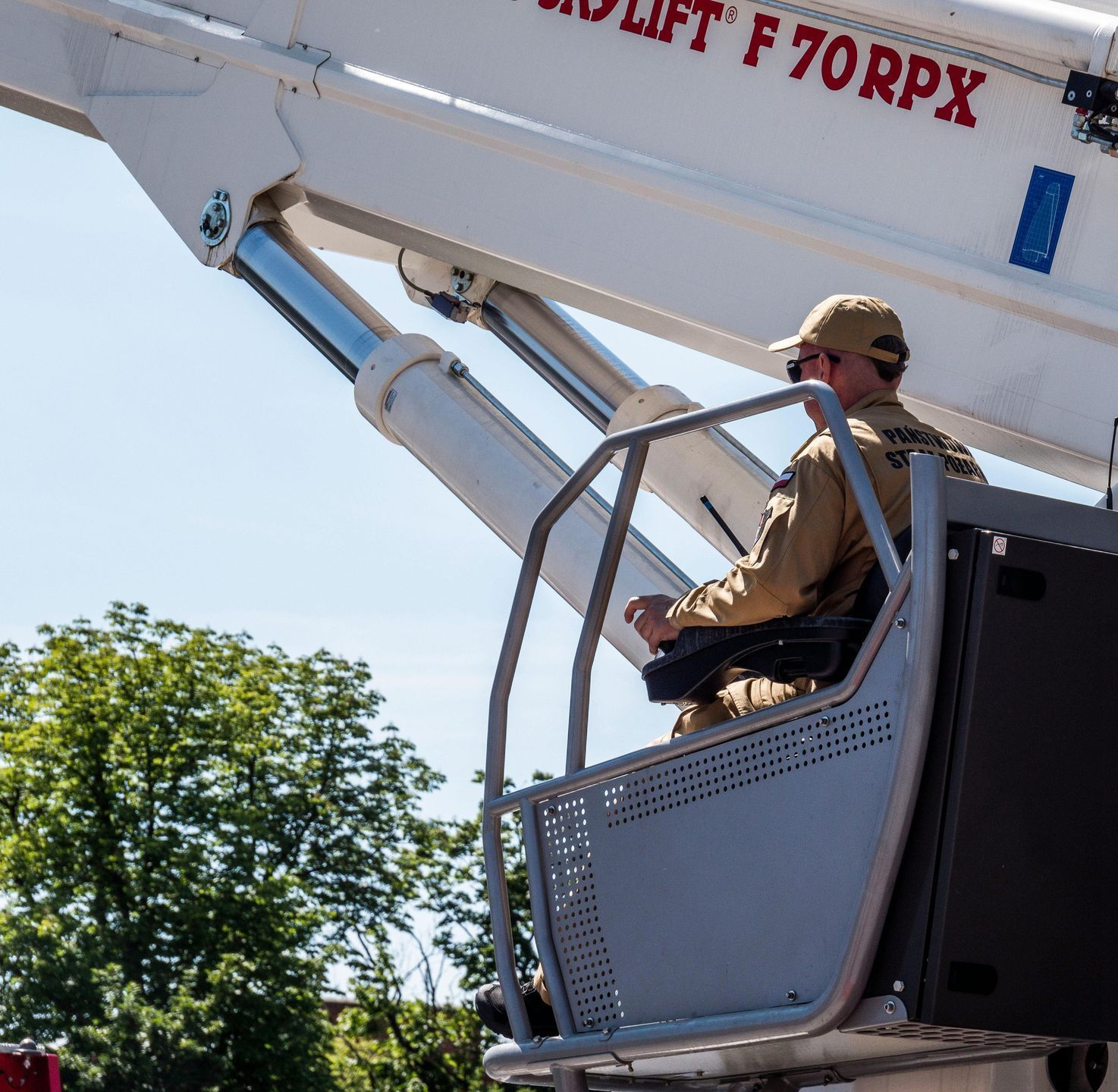 A man is sitting in a bucket on a crane that says f70rpx