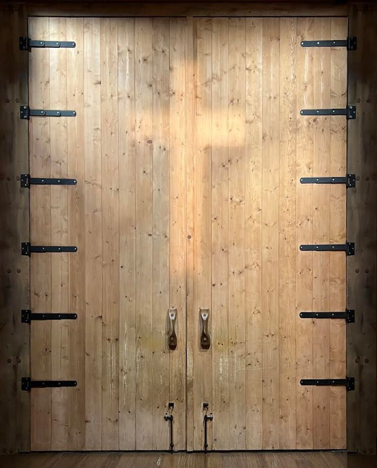 The massive wooden door of the Noah's Ark Encounter in Kentucky, featuring a prominent cross projected onto its surface.