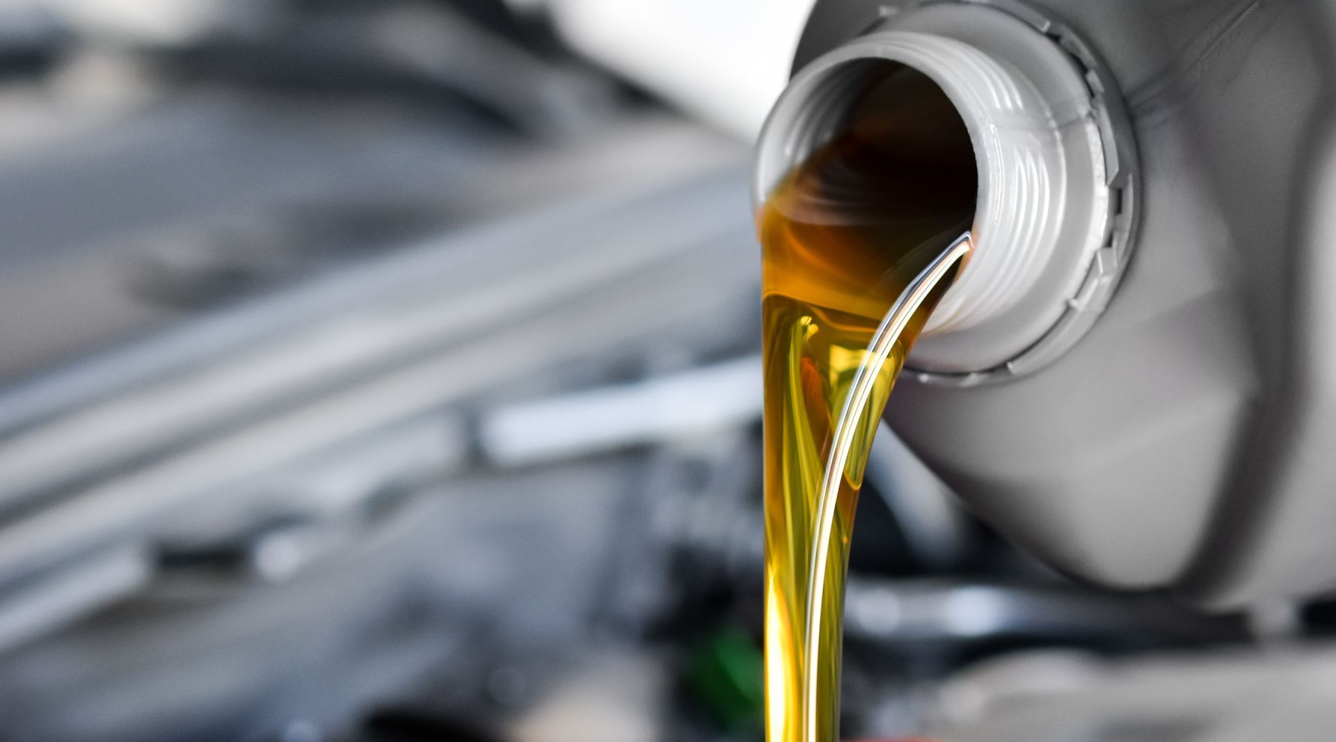 Image showing fresh car oil being poured into the oil filler tube during a routine oil change.