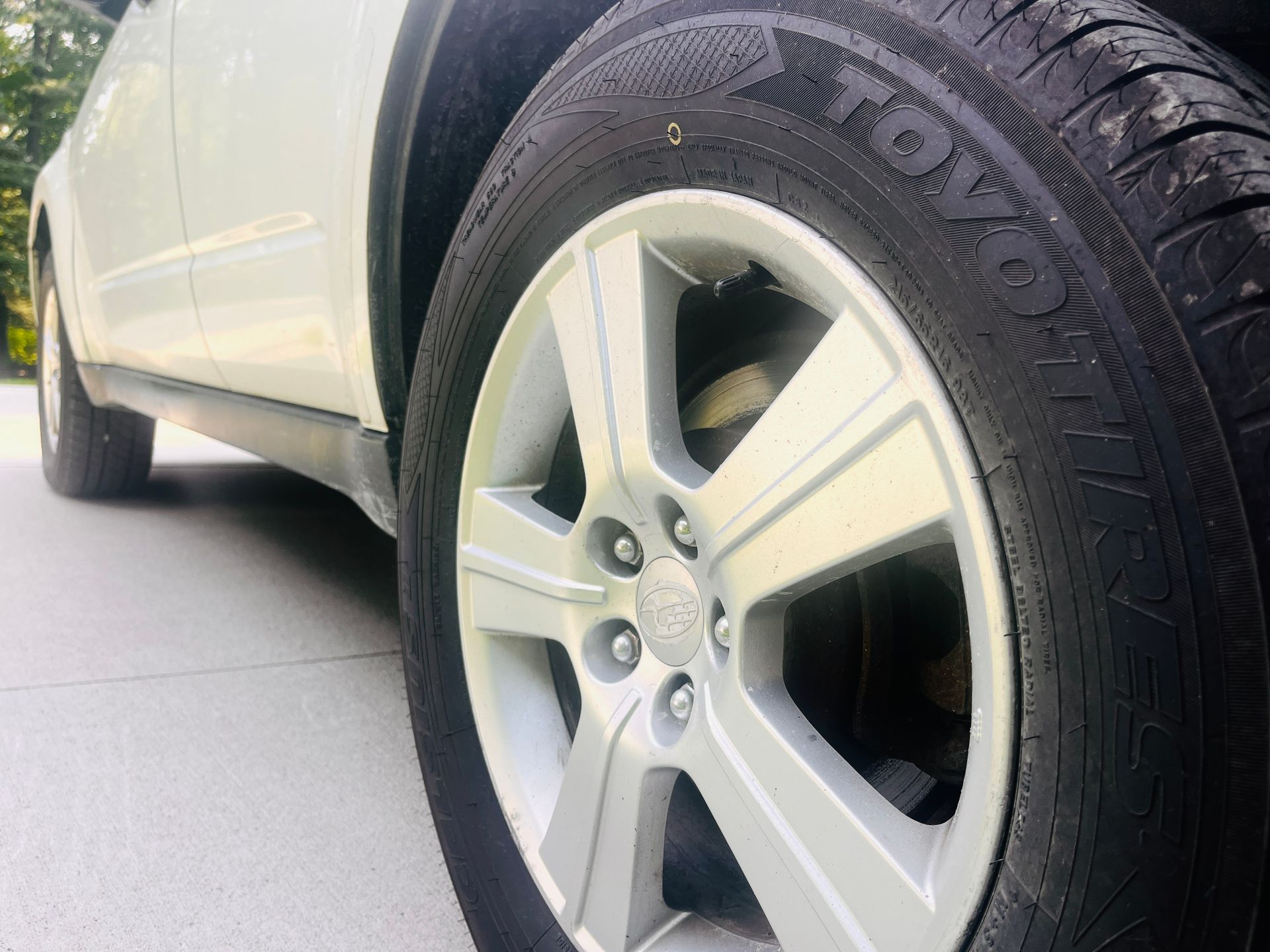 Close-up of a car tire with detailed tread pattern with part of the car's body visible