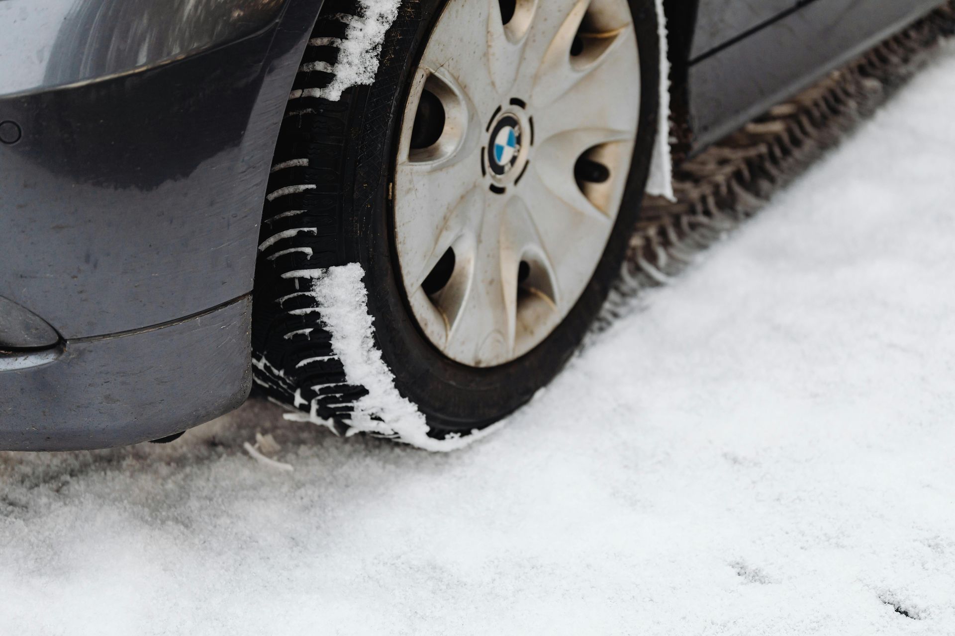 Close-up of a tire partially covered in snow, showcasing tread patterns designed for winter traction.