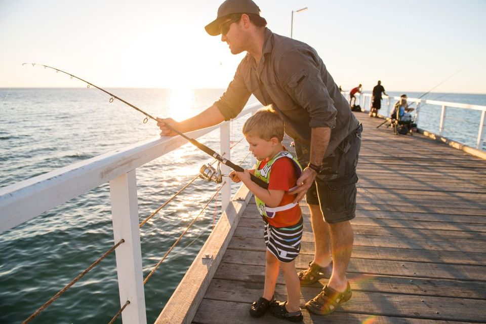 A man and a boy are fishing on a pier.