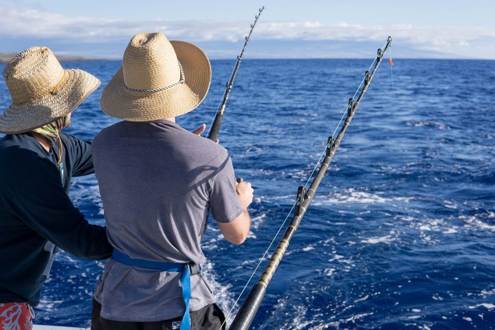 Two men are fishing in the ocean on a boat.