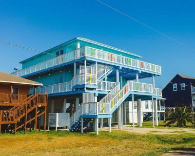 A blue house with stairs leading up to it is sitting on top of a lush green field.