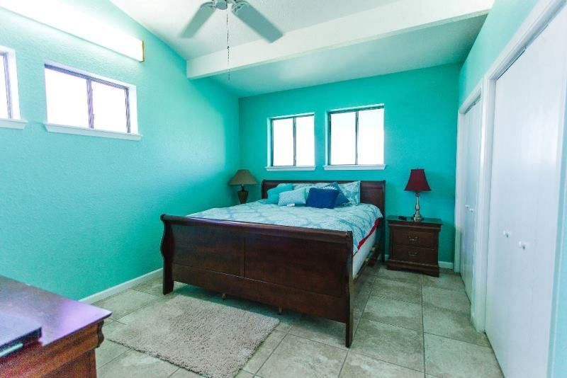 A bedroom with a king size bed and a ceiling fan