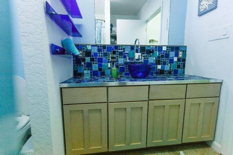 A bathroom with a blue tiled wall and a sink