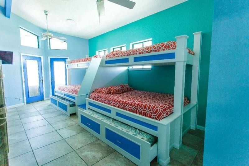 A bedroom with three bunk beds and a ceiling fan.