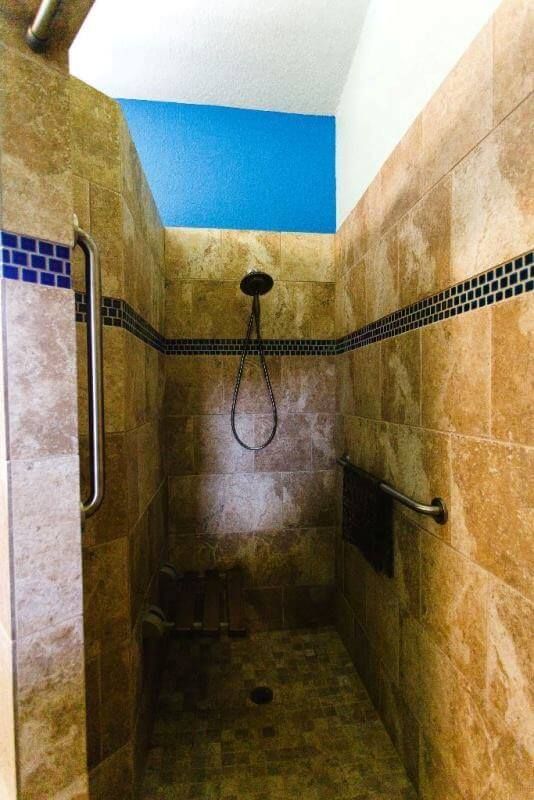 A bathroom with a walk in shower and a blue wall.