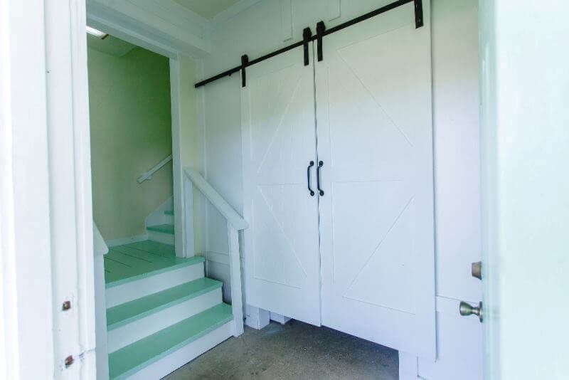A hallway with stairs and a sliding barn door.