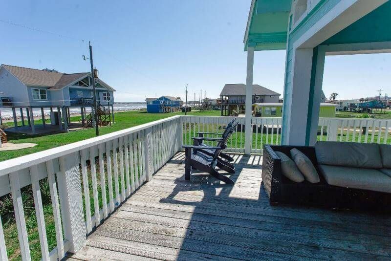 A deck with a couch and chairs and a view of the ocean