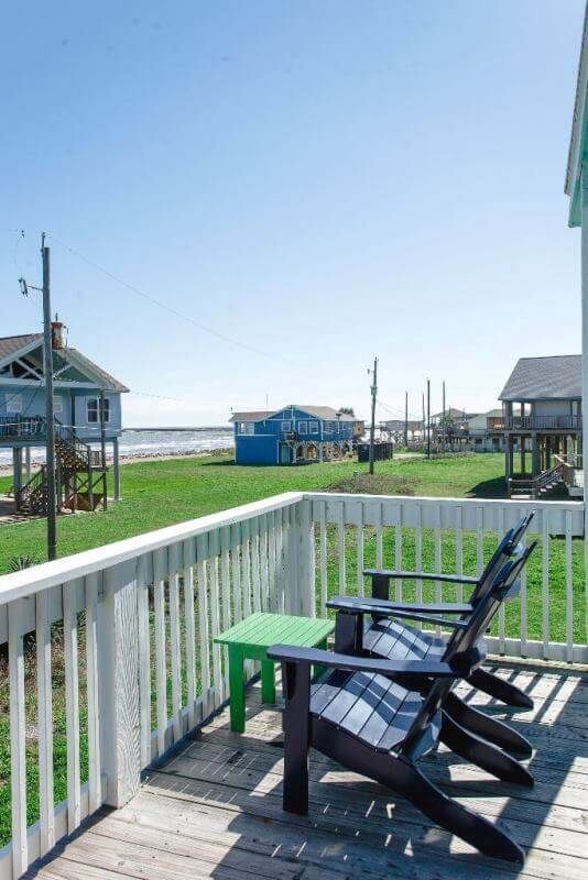 A deck with two chairs and a table with a view of the ocean.