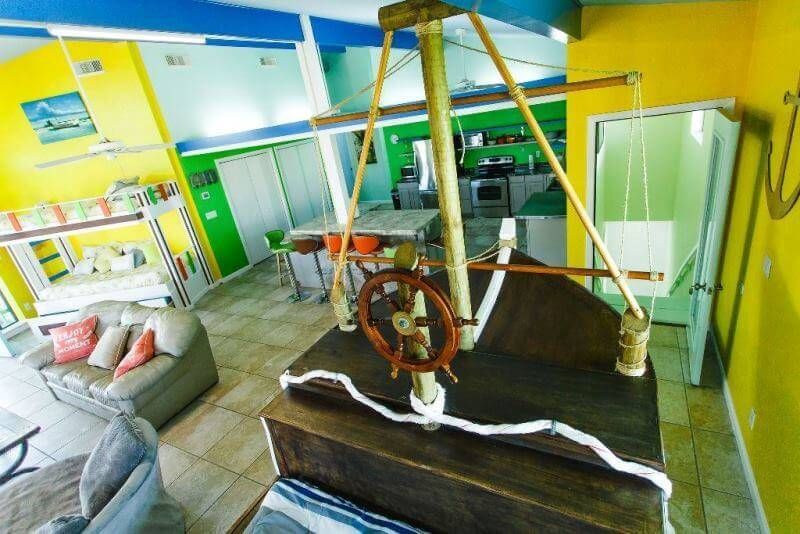 A living room with a boat steering wheel hanging from the ceiling